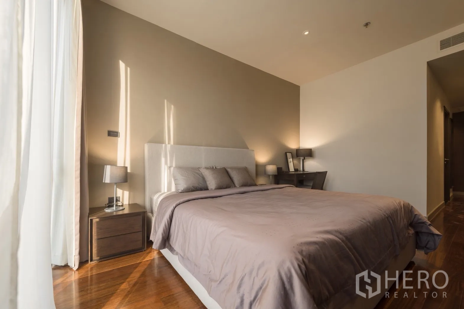 Condominium for rent in Khlong Toei, Bangkok - Bedroom with upholstered headboard, bedside lamps and work desk.