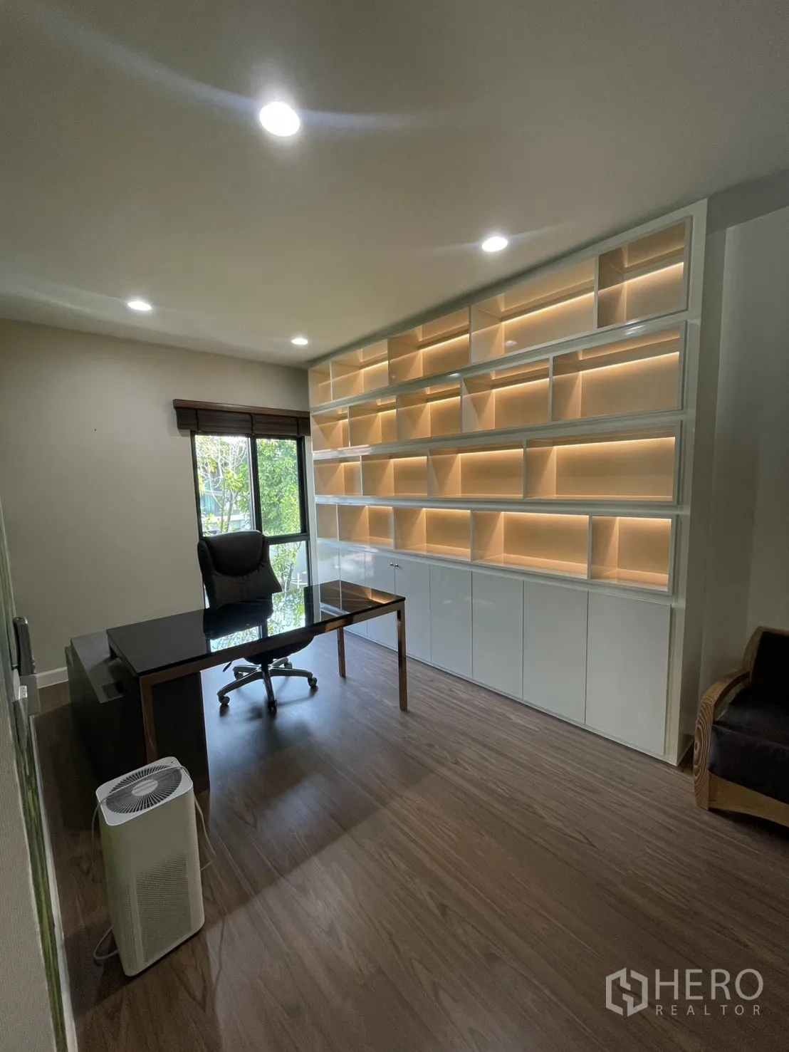Detached House for rent or sale in Lam Luk Ka, Pathum Thani - Home office with long built-in illuminated shelving, desk and window overlooking greenery.