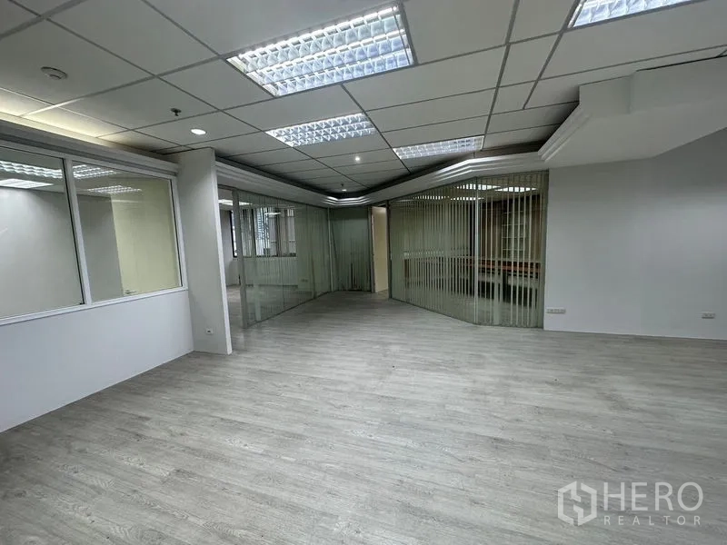 办公空间 出租在Din Daeng, Bangkok - 带玻璃隔断和垂直百叶的角落办公区，地面明亮。