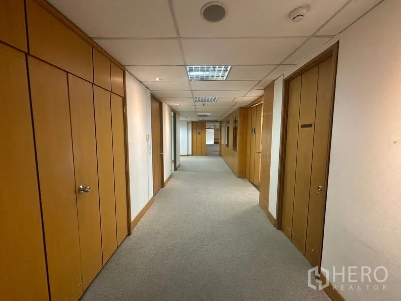 Office Space for rent in Khlong Toei, Bangkok - Carpeted corridor on an office floor with wood-paneled doors and recessed ceiling lights.