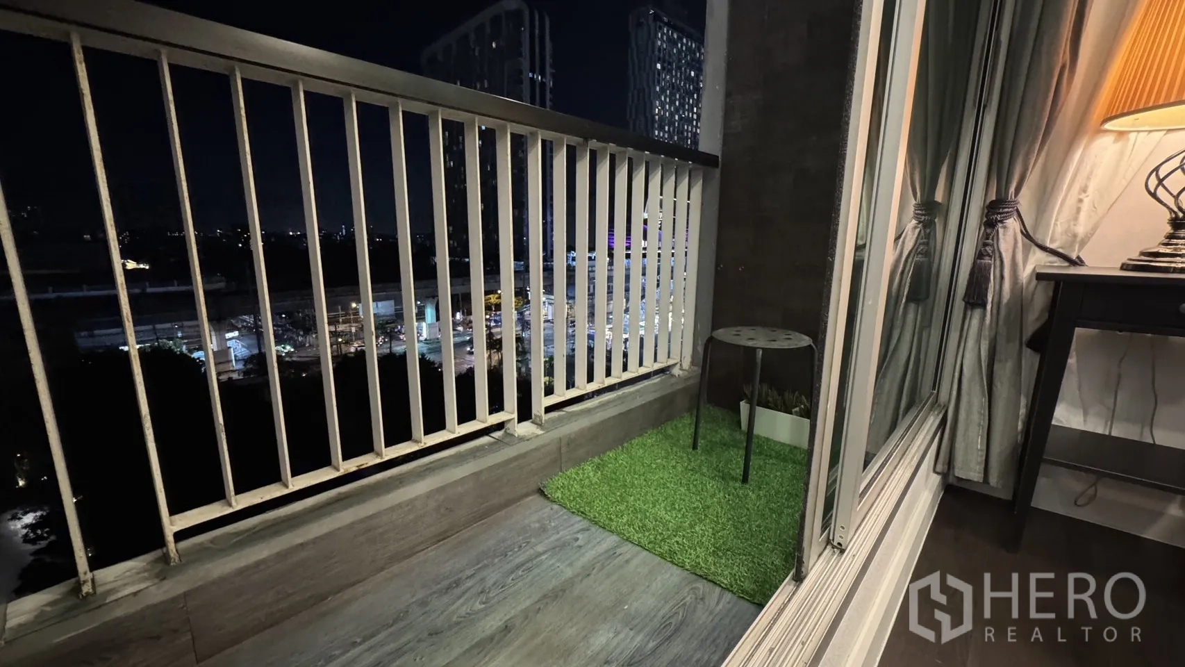 Condominium for rent or sale in Khlong Toei, Bangkok - Private balcony at night with city views, wood-look floor and a small grass mat.