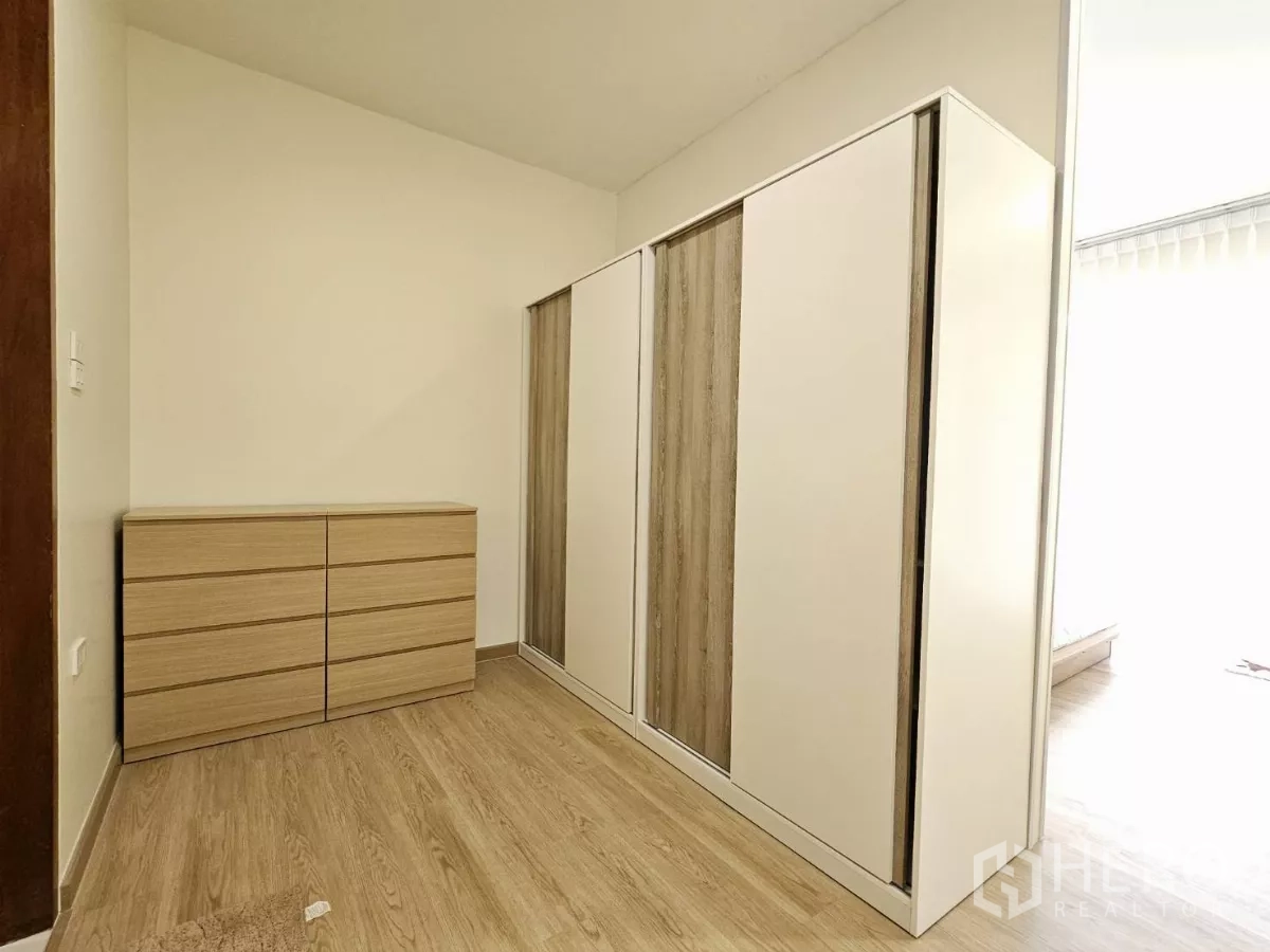 Townhouse for sale in Lat Phrao, Bangkok - Walk-in closet area with sleek wardrobes and a matching dresser.