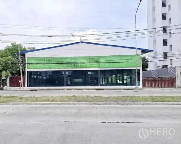 货栈 出租在Bang Kapi, Bangkok - 曼谷邦甲皮主干道上的仓库外观，玻璃橱窗立面与绿色装饰板，门面显眼。