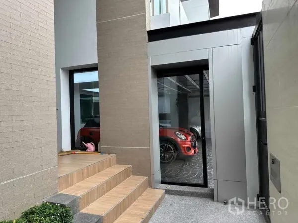 Detached House for sale in Suan Luang, Bangkok - Private entrance with tiled steps and a glass door looking into a covered carport with a red vehicle.