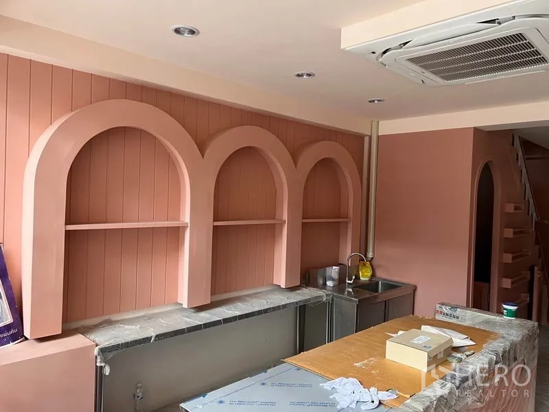 Shophouse for rent or sale in Watthana, Bangkok - Built-in arched display shelves above a stone counter with stainless sink and cassette AC.