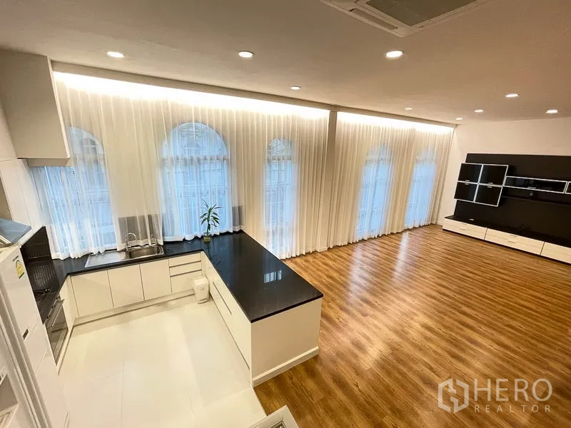 Townhouse for rent in Yan Nawa, Bangkok - Bright living space with recessed lighting, arched windows and sleek kitchen with black worktop and built-in cabinets.