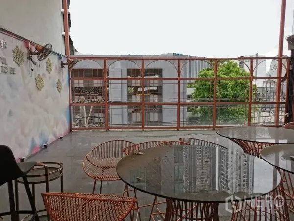 Shophouse for rent or sale in Watthana, Bangkok - Covered rooftop terrace with round tables, wire chairs and urban city views.