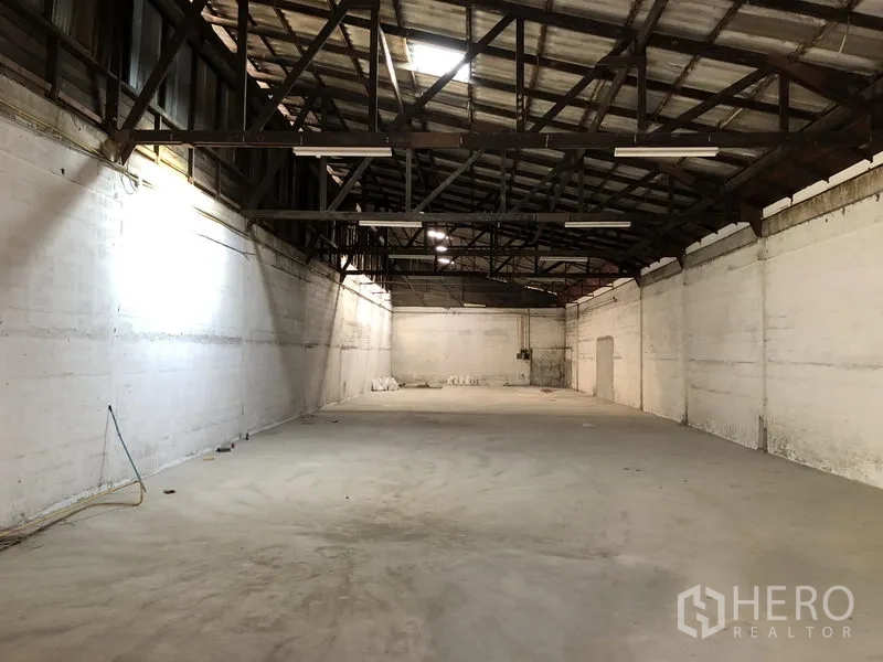 零售空间 出租在Khlong Toei, Bangkok - 宽敞的仓库式零售室内，高挑钢桁架天花、白色墙面与混凝土地面。
