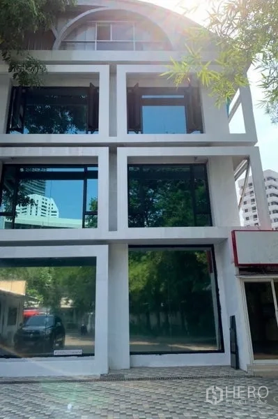 Standalone for rent in Khlong Toei, Bangkok - Modern standalone building exterior with large glass panels and on-site parking in Khlong Toei, Bangkok.