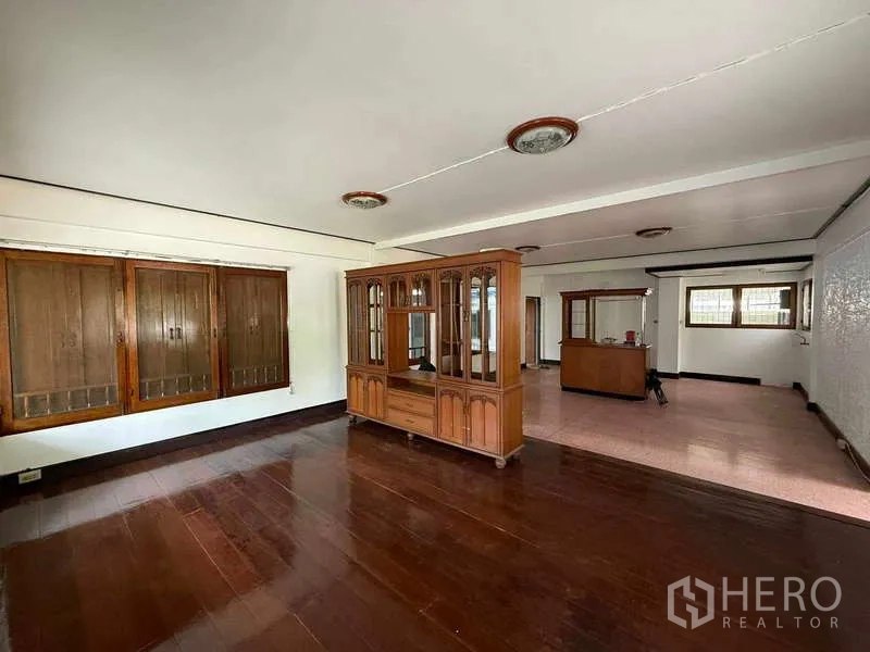 Detached House for rent in Watthana, Bangkok - Open‑plan living area with wooden floors, built‑in cabinets and large windows.