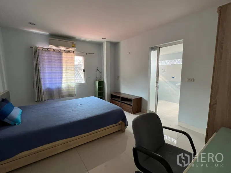 Detached House for rent in Bang Kapi, Bangkok - Bedroom with study desk, air conditioning and ensuite bathroom through sliding door.