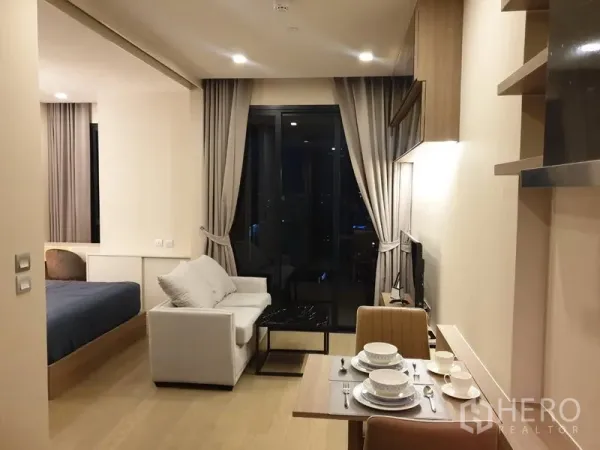 คอนโด ให้เช่าในWatthana, Bangkok - ห้องนั่งเล่นแบบเปิดโล่ง มีโซฟา ทีวี ประตูกระจกออกระเบียง เห็นโซนนอนด้านซ้าย วิวเมืองยามค่ำคืน