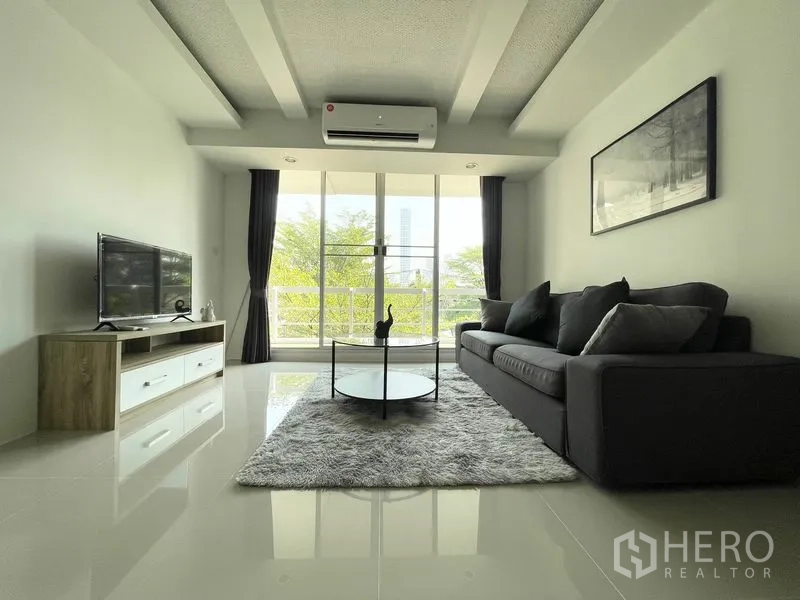 คอนโด for rent in Khlong Toei, Bangkok - ห้องนั่งเล่นหันสู่ประตูระเบียง พร้อมโซฟา ชั้นวางทีวี และวิวต้นไม้