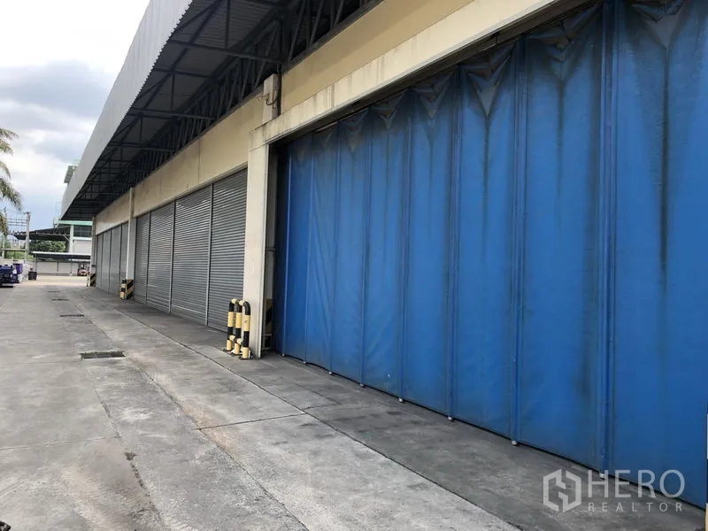 工厂 出租在Lam Luk Ka, Pathum Thani - 有顶装卸月台，设蓝色挡风帘与多道卷帘门。