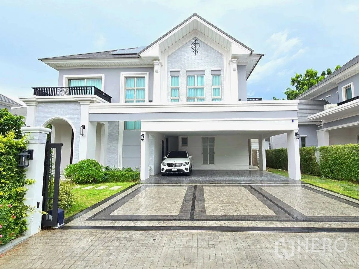 บ้านเดี่ยว for rent or sale in Bang Phli, Samut Prakan - ด้านหน้าบ้านหรูสองชั้นพร้อมทางรถกว้าง และที่จอดรถมีหลังคาในบรรยากาศยามเย็น