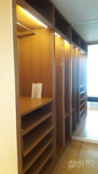Condominium for sale in Sathon, Bangkok - Walk-in closet with built-in wooden shelving and hanging space.