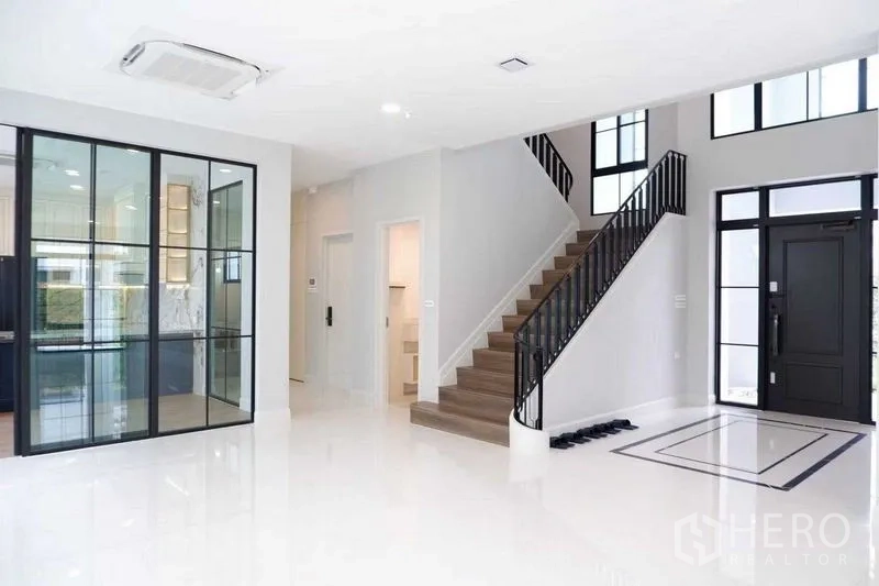 Detached House for sale in Saphan Sung, Bangkok - Entrance hall with staircase, glass-enclosed kitchen area and large windows.