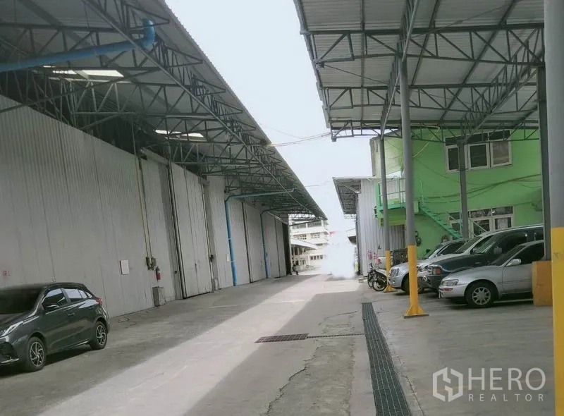 货栈 出租在Khlong Luang, Pathum Thani - 仓库楼栋之间的宽阔车道，带雨棚的装卸位与现场停车位。