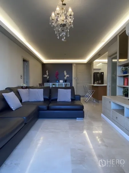 Condominium for rent in Bang Rak, Bangkok - Open-plan lounge with large leather sofa, chandelier lighting and polished marble floors.