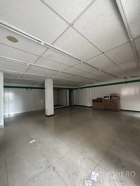 Retail Space for rent in Khlong Toei, Bangkok - Spacious tiled showroom area with columns and fluorescent lighting.