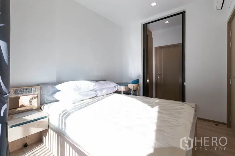 Condominium for rent in Watthana, Bangkok - Sunlit bedroom with bed, bedside table and sliding door to the living room.