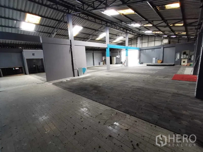 Warehouse for rent in Nonthaburi - Spacious warehouse area with steel columns, roof light panels and a raised platform.