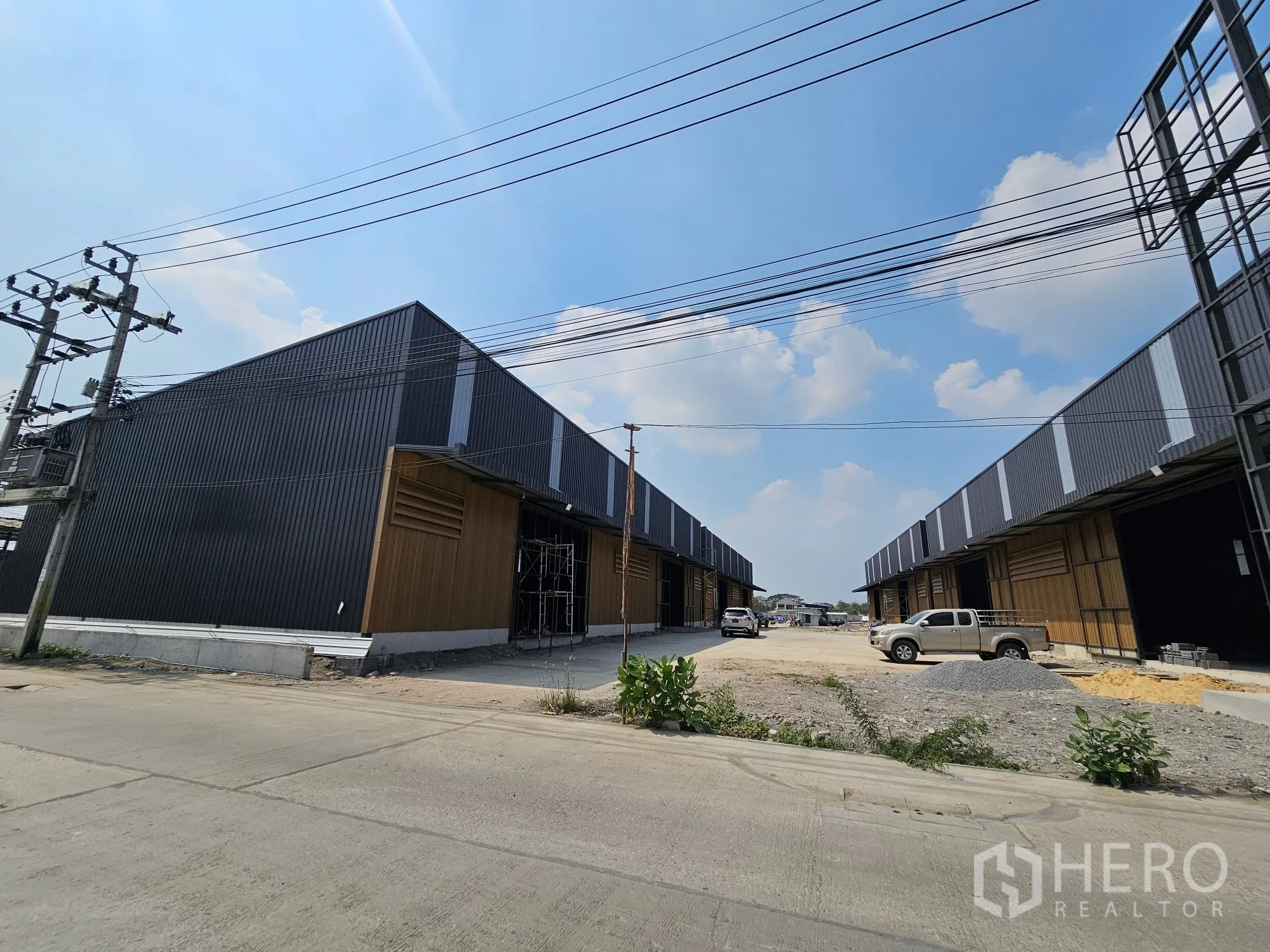 โกดัง for rent in Bang Khen, Bangkok - อาคารโกดังหลายยูนิตพร้อมถนนภายในกว้างและสายไฟเหนือศีรษะ
