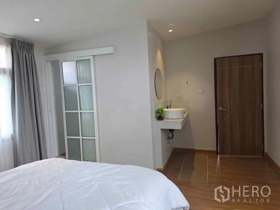 独立式住宅 出租在Khlong Toei, Bangkok - 卧室带独立洗手台，磨砂推拉门通往浴室，木地板。