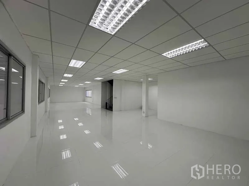 Factory for rent in Khlong Luang, Pathum Thani - Clean modern office space with white tile flooring, suspended ceiling and fluorescent lighting.