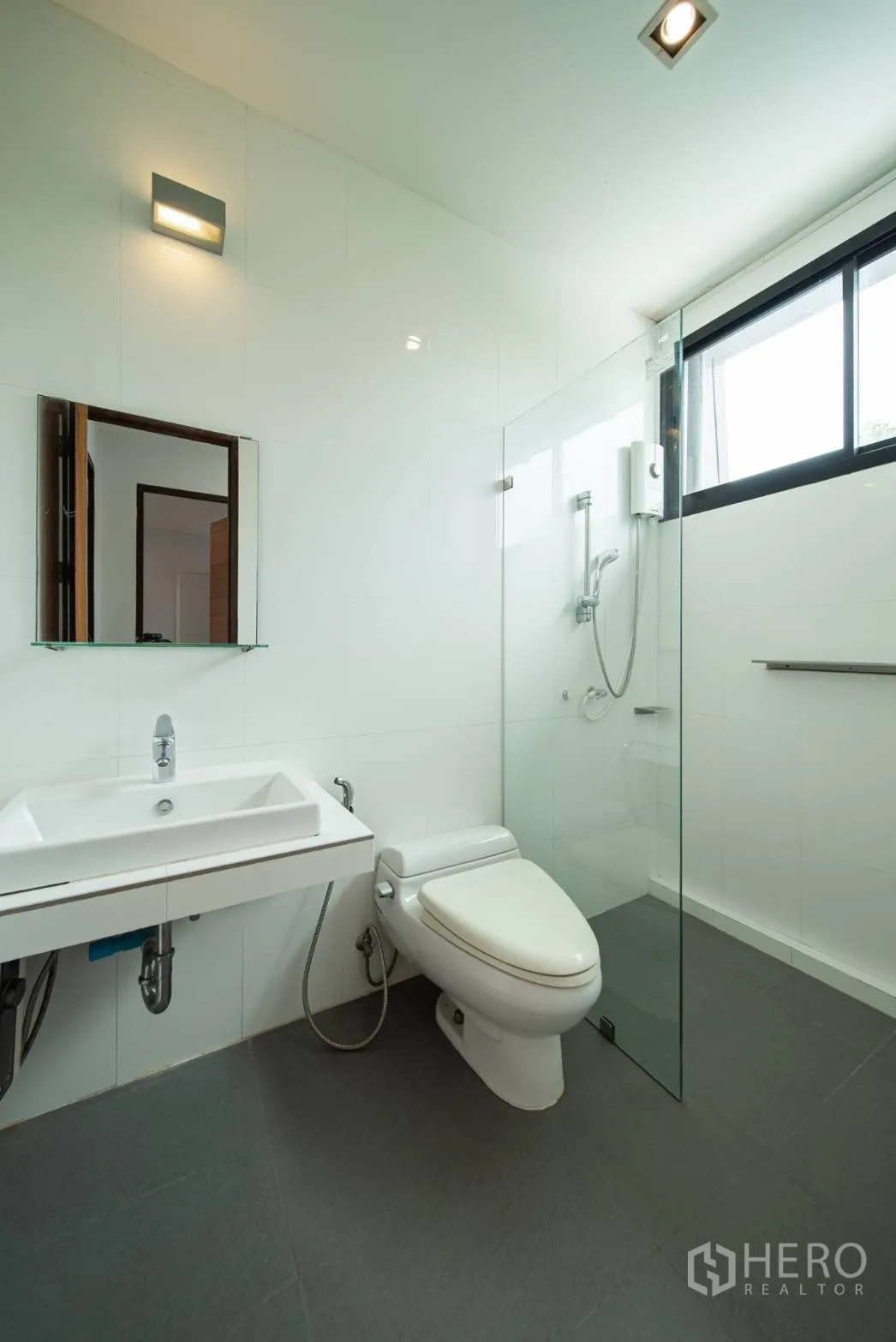 Townhouse for rent in Watthana, Bangkok - Bright bathroom with glass shower enclosure, toilet and vanity.