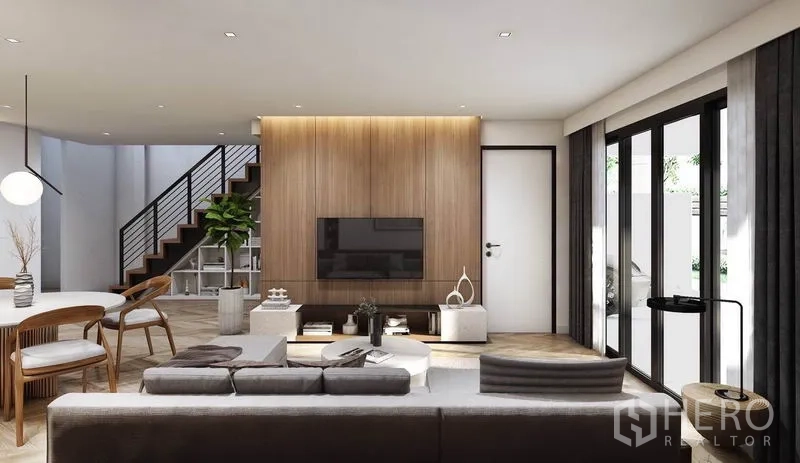Detached House for rent in Watthana, Bangkok - Bright living room featuring a wood accent wall, large sliding glass doors, and a staircase.