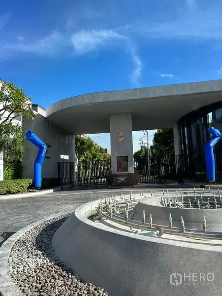 Townhouse for rent in Saphan Sung, Bangkok - Gated community entrance with security gate and fountain roundabout.