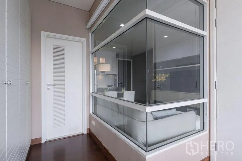 Condominium for rent or sale in Watthana, Bangkok - Interior corridor with large glass partition and white door beside the bedroom.