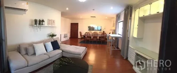 Condominium for rent or sale in Din Daeng, Bangkok - Wide view of the open-plan condo showing lounge, study nook and dining space with wood flooring.