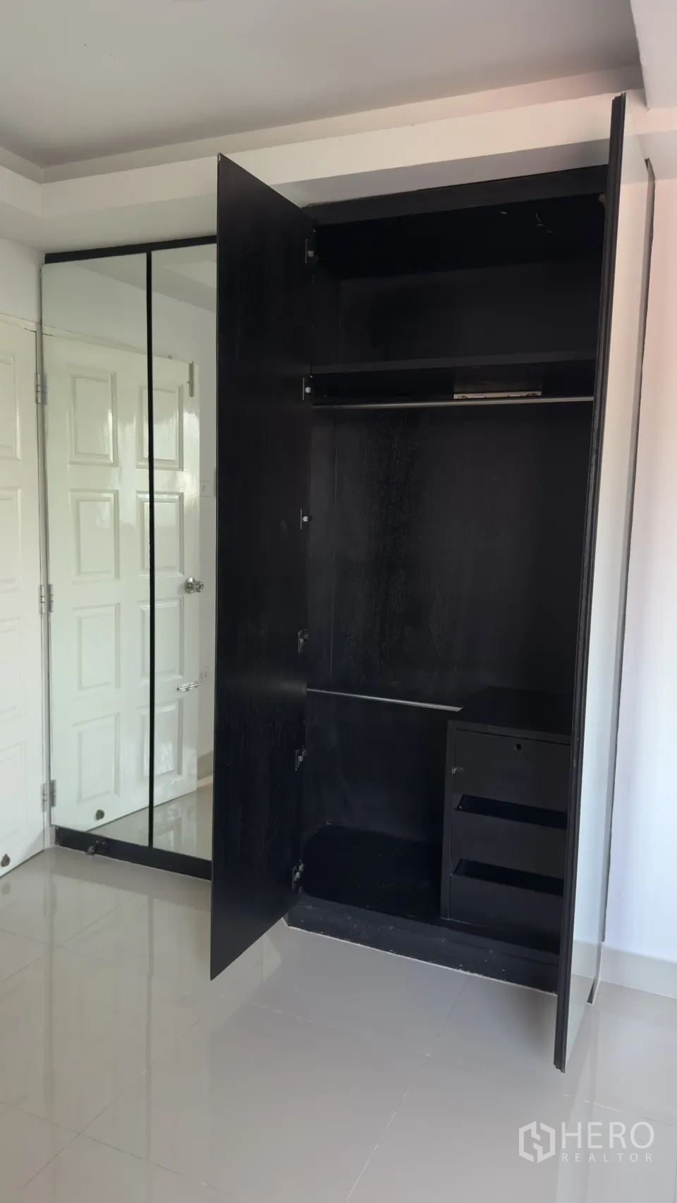 联排别墅 for rent in Watthana, Bangkok - 白色卧室内打开的黑色衣柜，带镜面柜门与挂衣空间。