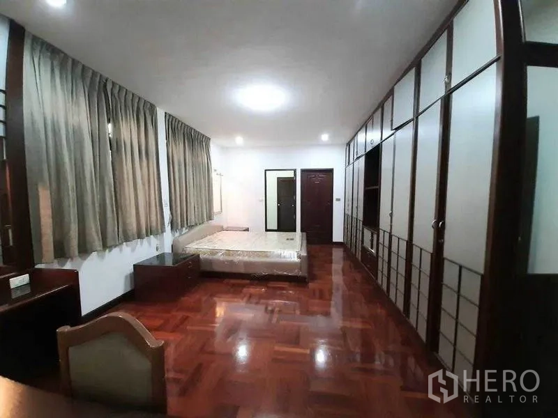 Detached House for rent in Watthana, Bangkok - Generous bedroom featuring extensive wardrobes, bed and wood floors.