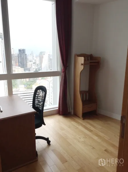 Condominium for rent in Khlong Toei, Bangkok - Study corner with desk, office chair and tall window overlooking the city.