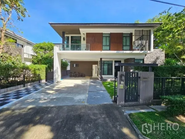 独立式住宅 出售在Prawet, Bangkok - 两层住宅正立面，宽车道、大门与修剪整齐的草坪。