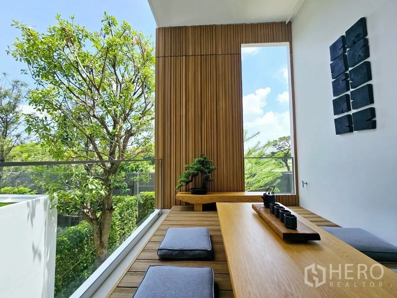 Detached House for rent in Saphan Sung, Bangkok - Tea corner balcony with low table, floor cushions, and bonsai against wood panels.