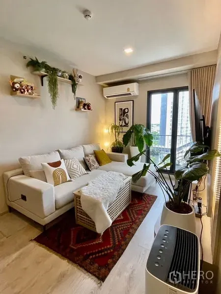 Condominium for sale - Bright living room with white sofa, indoor plants, balcony and city view at The Tree Pattanakarn-Ekkamai.