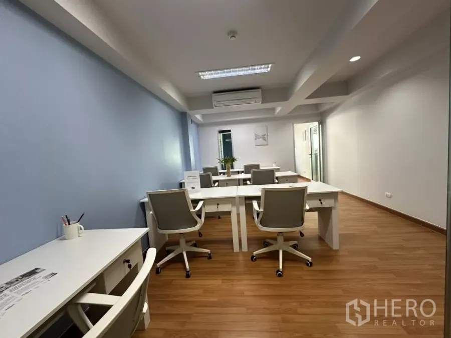 办公空间 出租在Watthana, Bangkok - 开放式通罗办公室，白色工位与灰色椅子，木地板与蓝色强调墙。