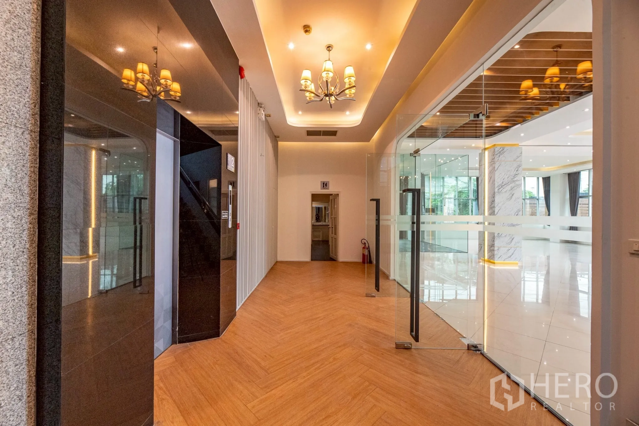 Office Space for rent in Wang Thonglang, Bangkok - Corridor beside the elevator with glass doors and warm recessed lighting.