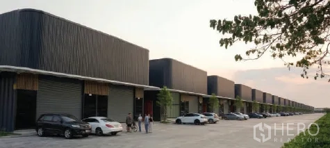 Warehouse for rent in Bueng Kum, Bangkok - Row of modern warehouse units with parking bays and a wide driveway.