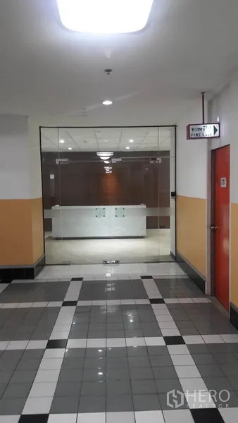 Office Space for rent in Huai Khwang, Bangkok - Office corridor with tiled floor leading to a glass-door entrance and reception in Huai Khwang, Bangkok.