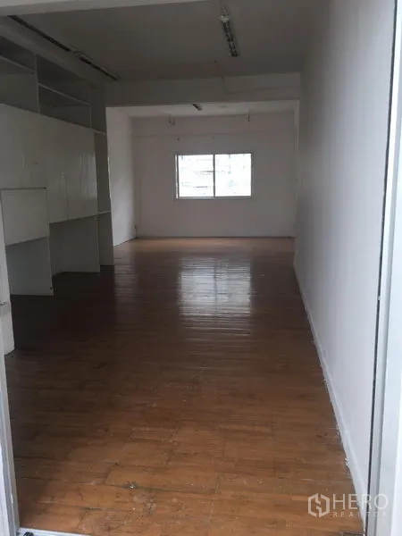 店屋 出租在Khlong Toei, Bangkok - 纵深店铺楼层，内置白色收纳柜，尾部窗户引入自然光。
