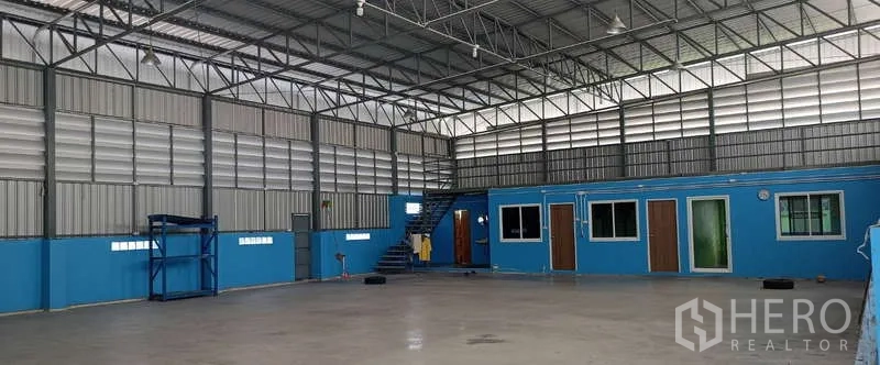 Warehouse for rent in Mueang Samut Sakhon, Samut Sakhon - Open floor warehouse with mezzanine walkway, internal office rooms and stair access beneath a metal roof.