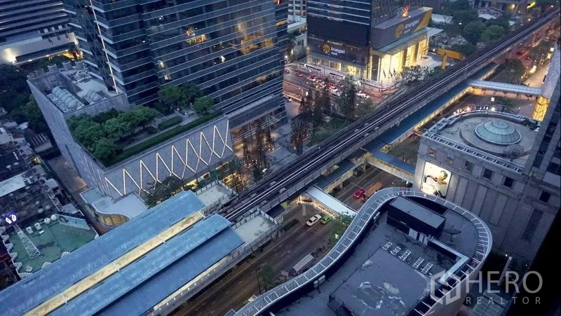 Condominium for rent in Pathum Wan, Bangkok - High-floor view of BTS Skytrain tracks and shopping malls around Chitlom at dusk.
