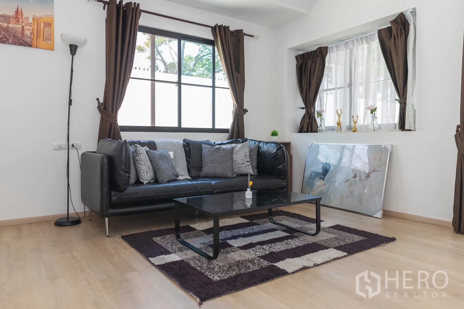 ทาวน์เฮาส์ for rent in Bang Phli, Samut Prakan - มุมนั่งเล่นโซฟาหนังสีดำ โต๊ะกาแฟ และพรมลายสี่เหลี่ยม