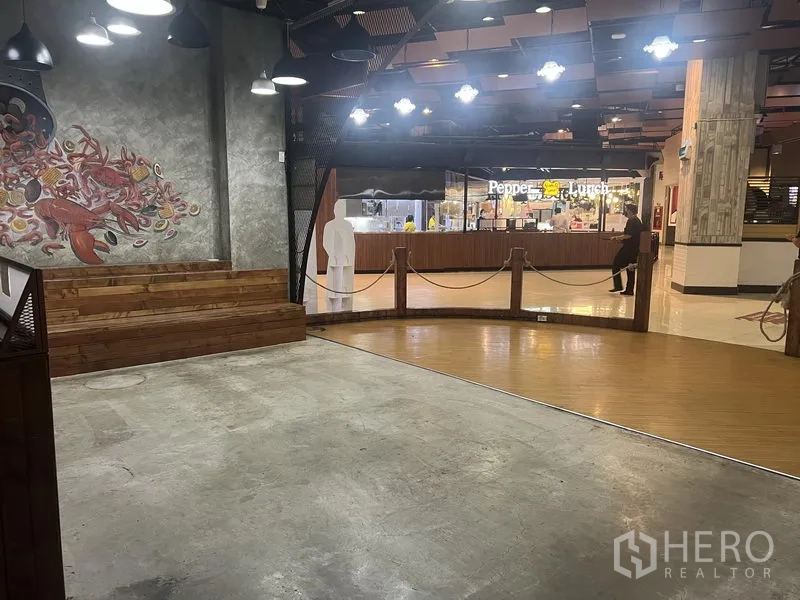 Retail Space for rent in Khlong Toei, Bangkok - Spacious open-plan area with raised wooden seating and rope barrier facing mall promenade and food kiosks.