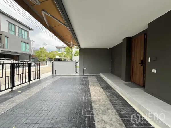 独立式住宅 出租在Prawet, Bangkok - 宽敞车库朝向小区安静街道与金属围栏。